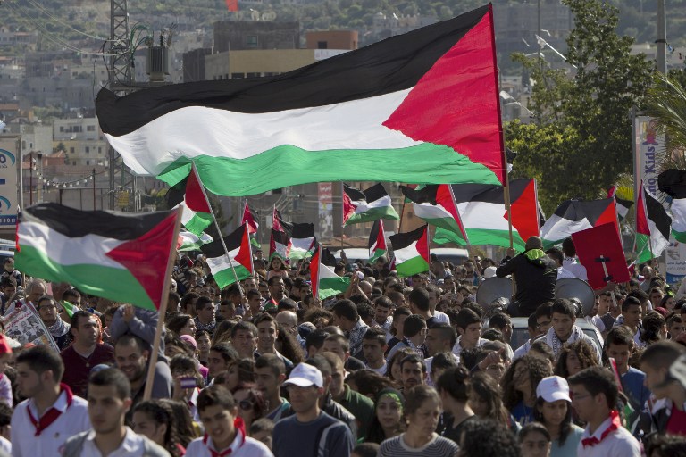 Arab Israelis wave Palestinian flags during a rally commemorating Land Day on March 30, 2014 in the northern Arab-Israeli town of Arrabe. The annual Land Day demonstrations are held to remember six Arab Israeli protesters who were shot dead by Israeli police and troops during mass demonstrations in 1976 against plans to confiscate Arab land in the Galilee. AFP PHOTO/AHMAD GHARABLI