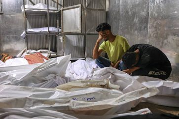 Palestinians mourn over the shrouded bodies of people killed the previous day while seeking aid near Zikim, west of Beit Lahia, in the northern Gaza Strip, at the morgue of at Al-Shifa hospital in Gaza City on August 10, 2025. Nearly two years into the war in Gaza, Israel's Prime Minister Benjamin Netanyahu faces mounting pressure to secure a truce to pull the territory's more than two million people back from the brink of famine and free the hostages held by Palestinian militants. (Photo by Omar AL-QATTAA / AFP) (Photo by OMAR AL-QATTAA/AFP via Getty Images)